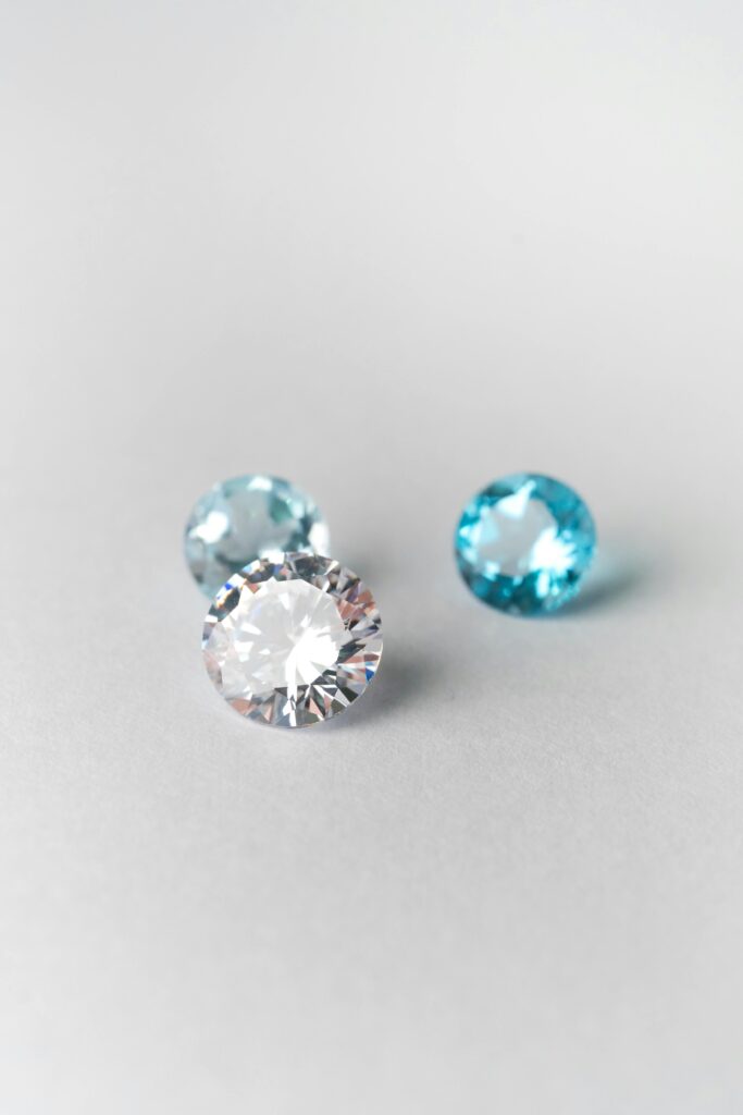 Close-up of sparkling blue and white gemstones on a smooth white surface, showcasing brilliance.